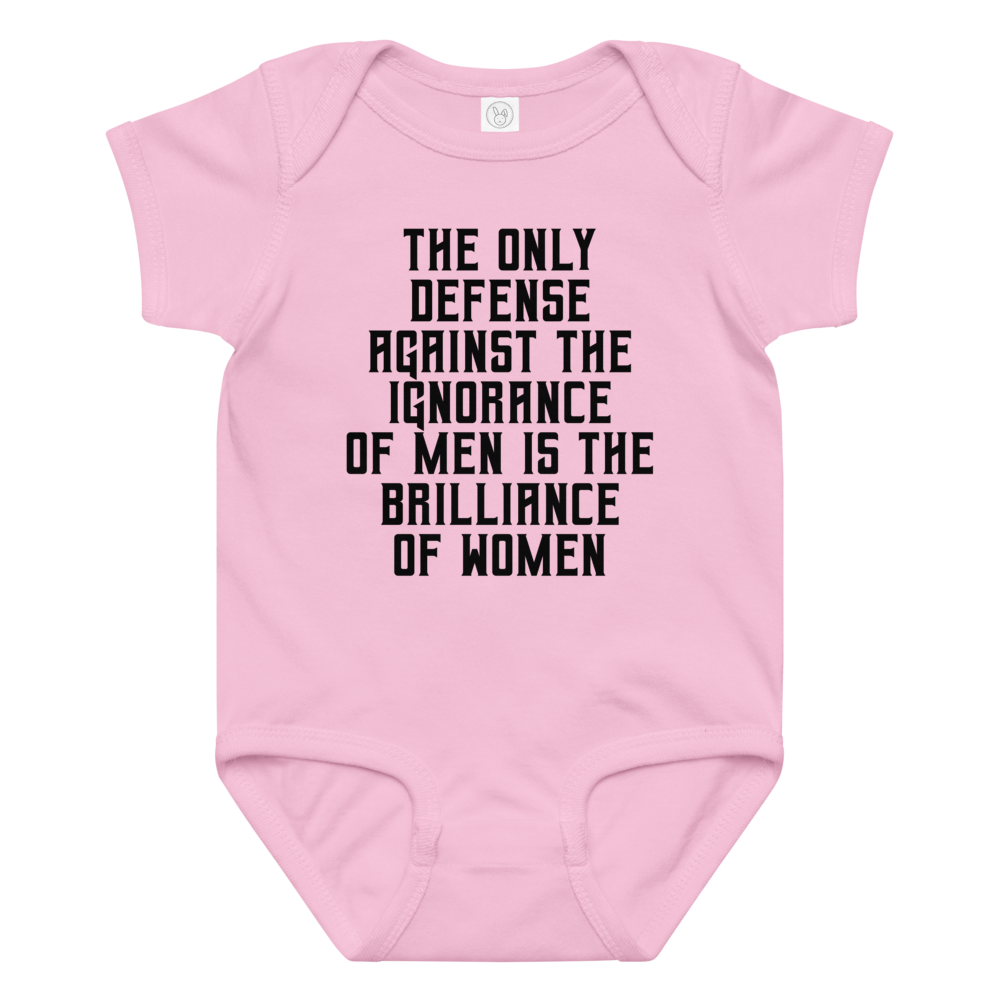 "The Only defense against the ignorance of men is the brilliance of women" printed on a pink baby jersey bodysuit laying on a flat surface amongst other clothes