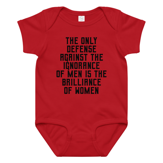 "The Only defense against the ignorance of men is the brilliance of women" printed on a red baby jersey bodysuit laying on a flat surface amongst other clothes