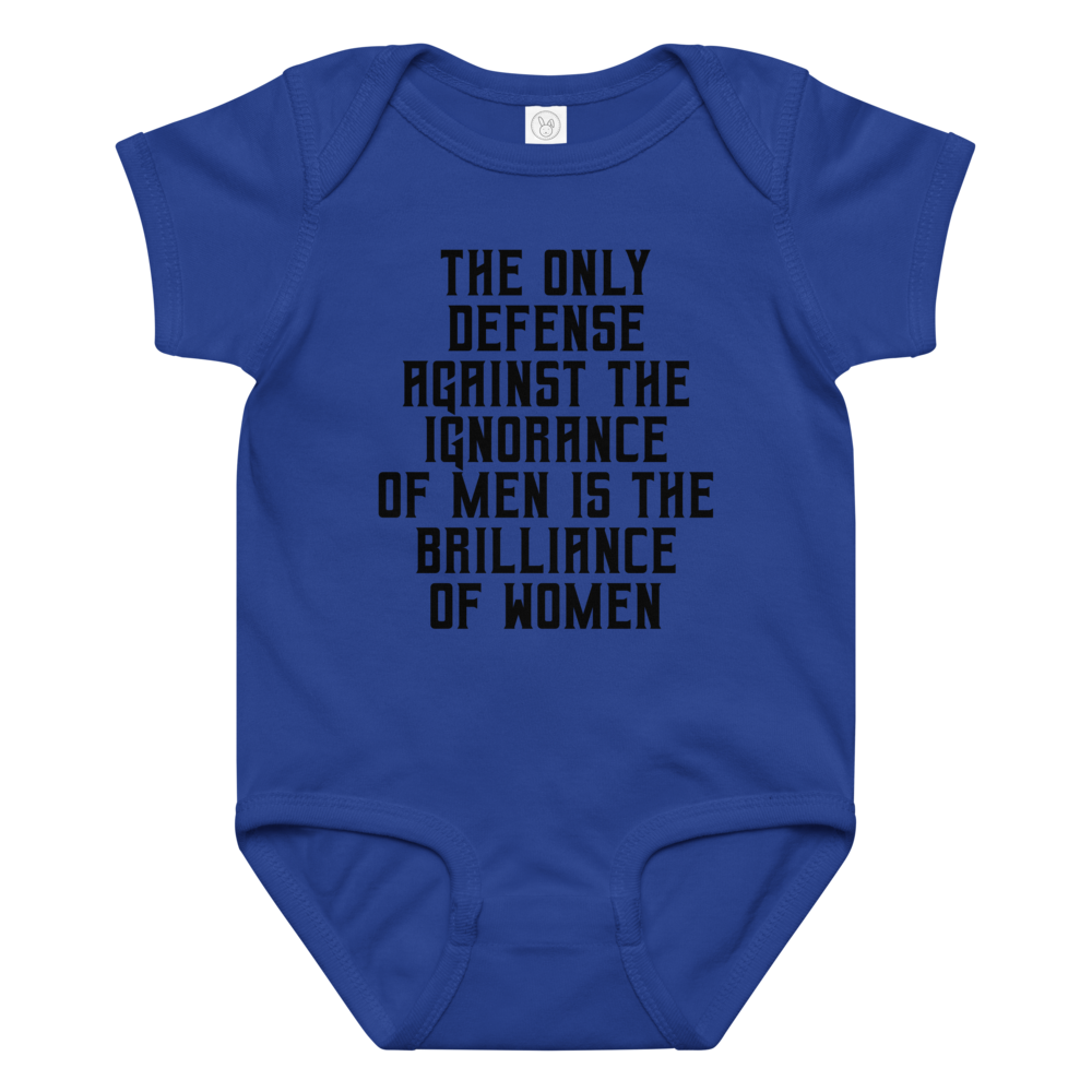 "The Only defense against the ignorance of men is the brilliance of women" printed on a royal baby jersey bodysuit laying on a flat surface amongst other clothes