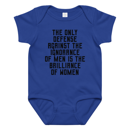 "The Only defense against the ignorance of men is the brilliance of women" printed on a royal baby jersey bodysuit laying on a flat surface amongst other clothes