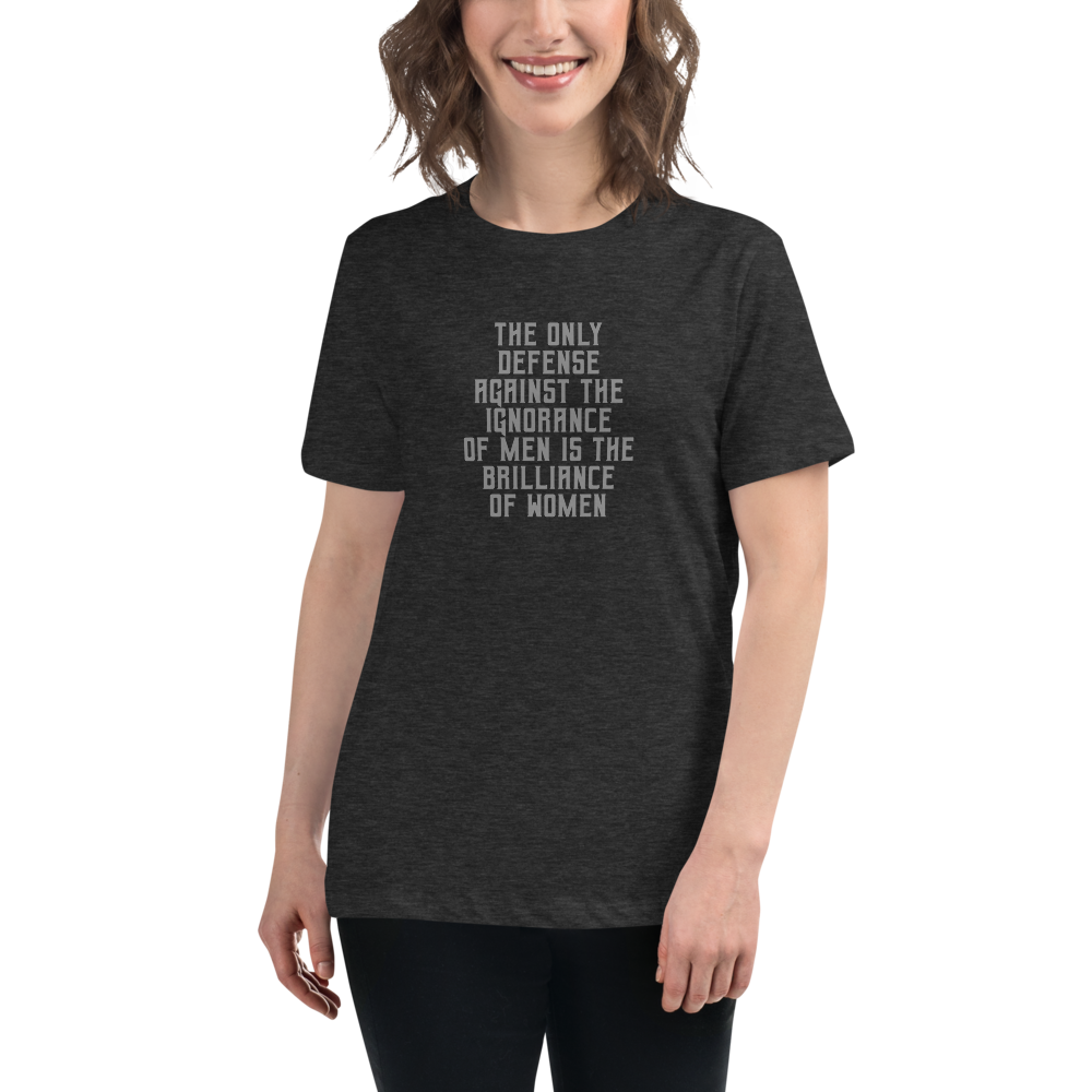 "The Only defense against the ignorance of men is the brilliance of women" printed on a dark grey heather women's relaxed t-shirt worn by a female
