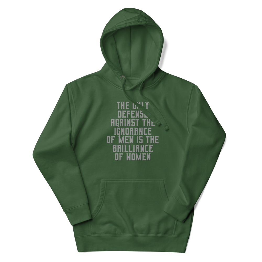 "The Only defense against the ignorance of men is the brilliance of women" printed on a forest green unisex hoodie laying on a flat surface with the hood up