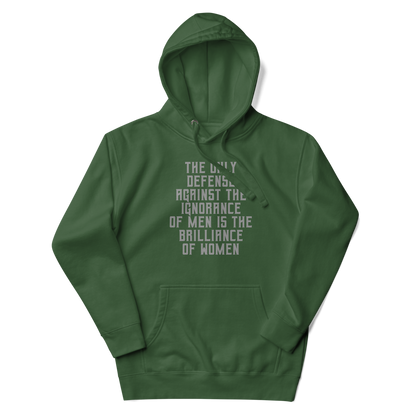 "The Only defense against the ignorance of men is the brilliance of women" printed on a forest green unisex hoodie laying on a flat surface with the hood up