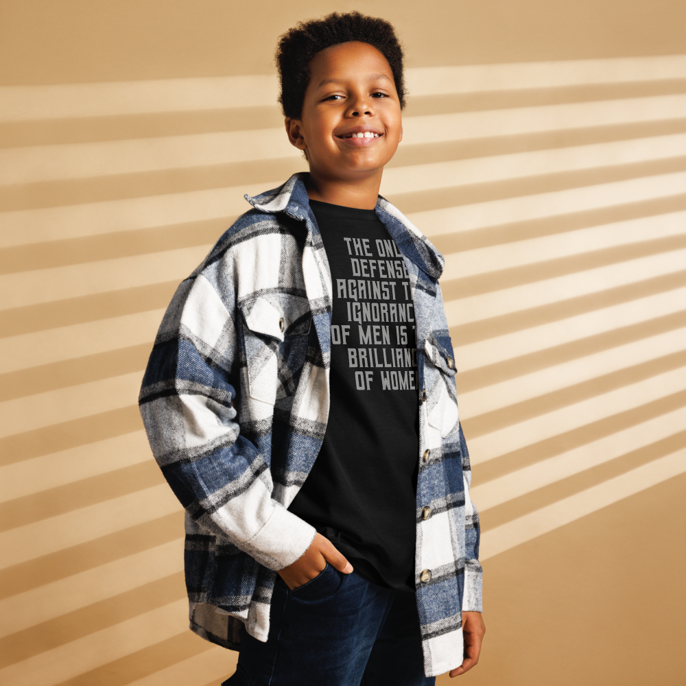 "The Only defense against the ignorance of men is the brilliance of women" printed on a black youth classic tee worn by a male also wearing a jacket