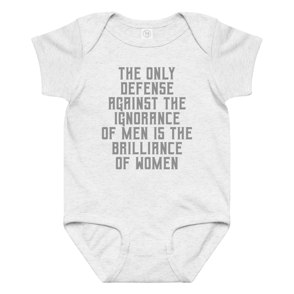 "The Only defense against the ignorance of men is the brilliance of women" printed on a ash baby jersey bodysuit laying on a flat surface amongst other clothes