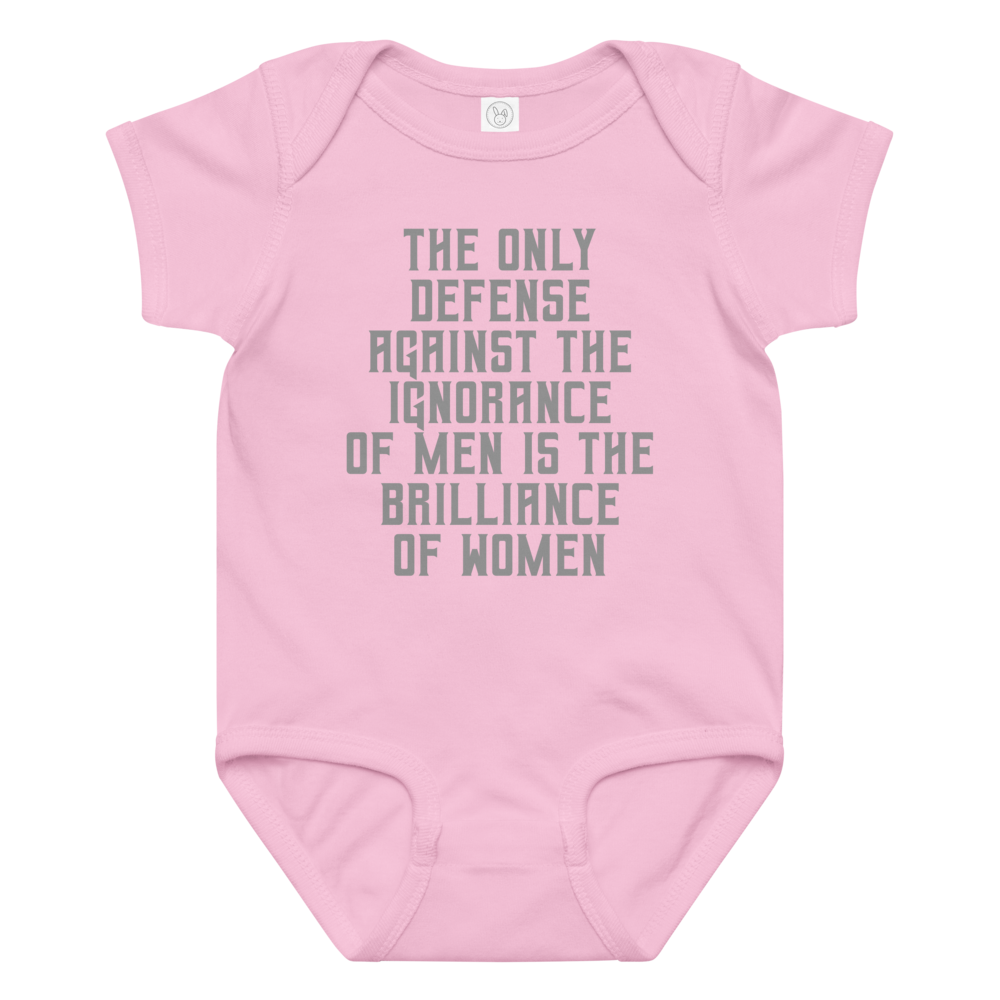 "The Only defense against the ignorance of men is the brilliance of women" printed on a pink baby jersey bodysuit laying on a flat surface amongst other clothes