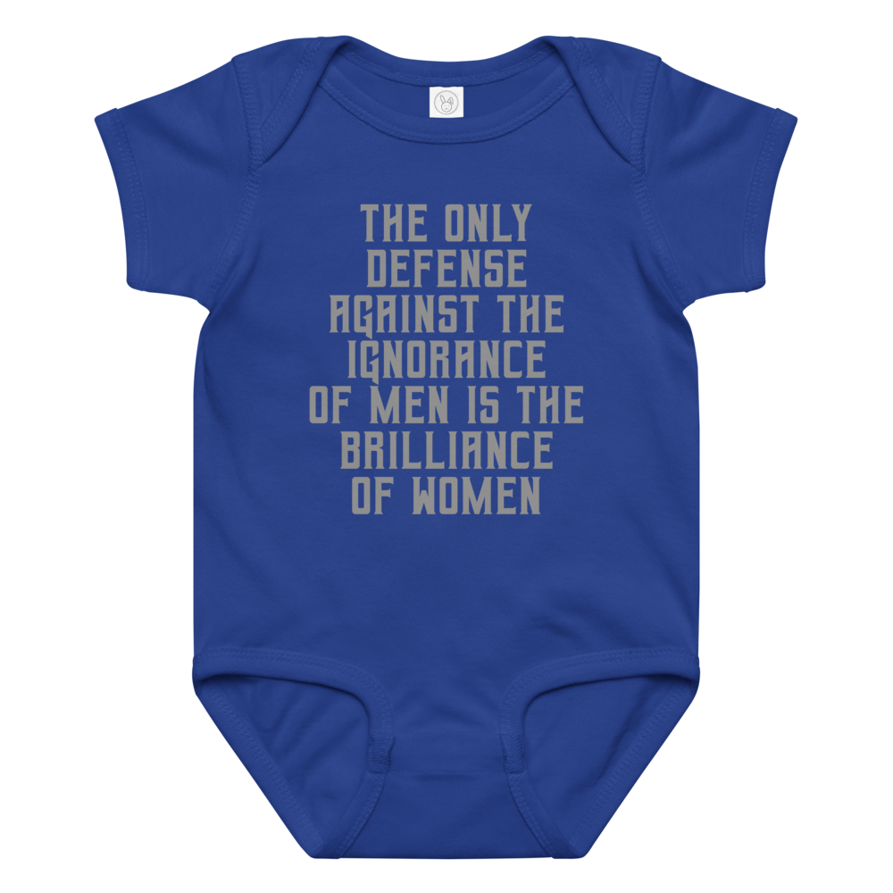 "The Only defense against the ignorance of men is the brilliance of women" printed on a royal baby jersey bodysuit laying on a flat surface amongst other clothes