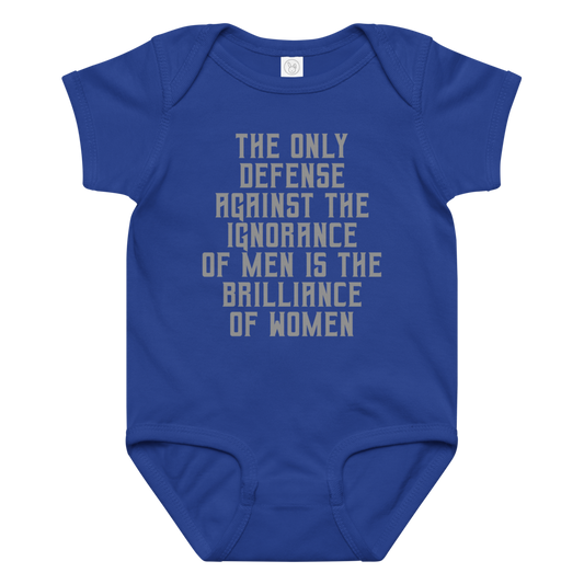 "The Only defense against the ignorance of men is the brilliance of women" printed on a royal baby jersey bodysuit laying on a flat surface amongst other clothes