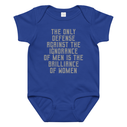 "The Only defense against the ignorance of men is the brilliance of women" printed on a royal baby jersey bodysuit laying on a flat surface amongst other clothes