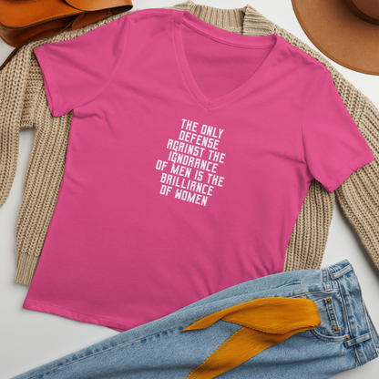 "The Only defense against the ignorance of men is the brilliance of women" printed on a berry women's relaxed v-neck t-shirt laying on a flat surface amongst other clothes