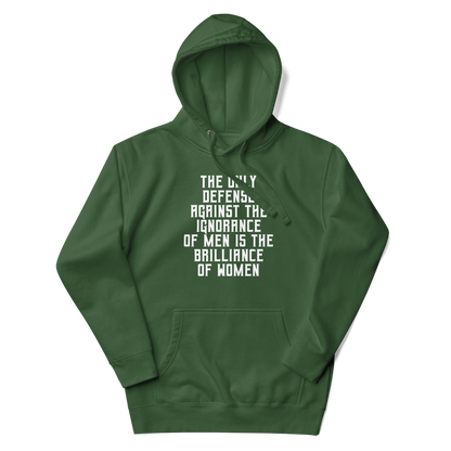 "The Only defense against the ignorance of men is the brilliance of women" printed on a forest green unisex hoodie laying on a flat surface with the hood up