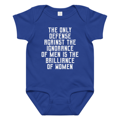 "The Only defense against the ignorance of men is the brilliance of women" printed on a royal baby jersey bodysuit laying on a flat surface amongst other clothes