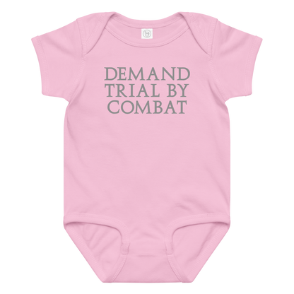 "Demand trial by combat" printed on a pink baby jersey bodysuit laying on a flat surface amongst other clothes