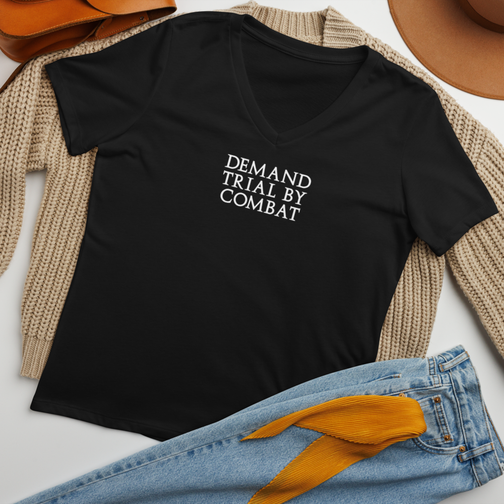 "Demand trial by combat" printed on a solid black blend women's relaxed v-neck t-shirt laying on a flat surface amongst other clothes