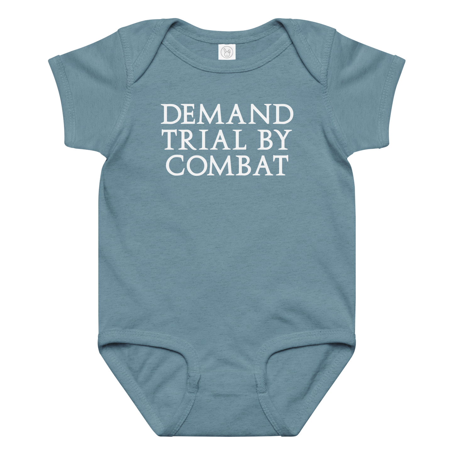 "Demand trial by combat" printed on a vintage indigo baby jersey bodysuit laying on a flat surface amongst other clothes