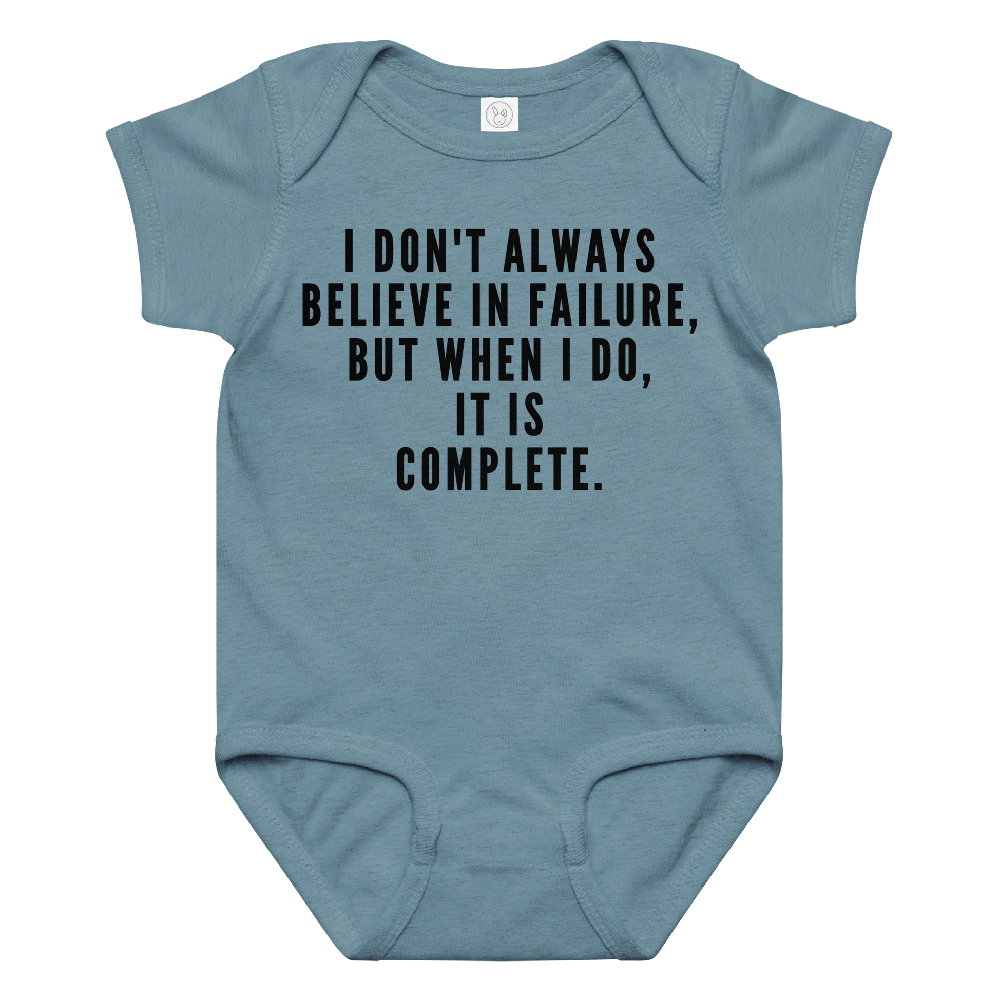 "I don't always believe in failure, but when I do, it is complete." printed on a vintage indigo baby jersey bodysuit laying on a flat surface amongst other clothes