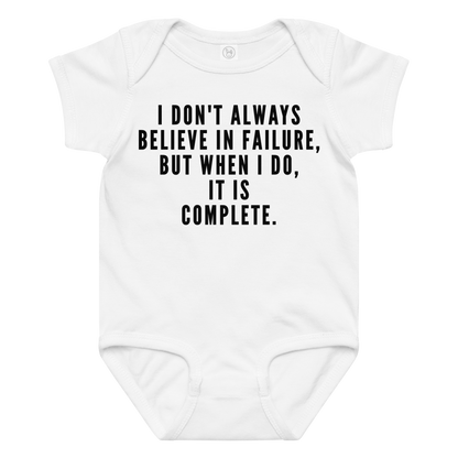"I don't always believe in failure, but when I do, it is complete." printed on a white baby jersey bodysuit laying on a flat surface amongst other clothes