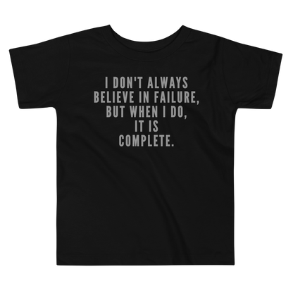 "I don't always believe in failure, but when I do, it is complete." printed on a black toddler short sleeve tee laying on a flat surface