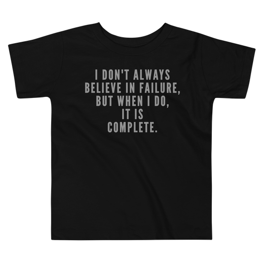 "I don't always believe in failure, but when I do, it is complete." printed on a black toddler short sleeve tee laying on a flat surface