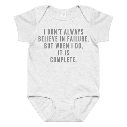 "I don't always believe in failure, but when I do, it is complete." printed on a ash baby jersey bodysuit laying on a flat surface amongst other clothes