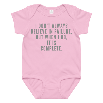 "I don't always believe in failure, but when I do, it is complete." printed on a pink baby jersey bodysuit laying on a flat surface amongst other clothes