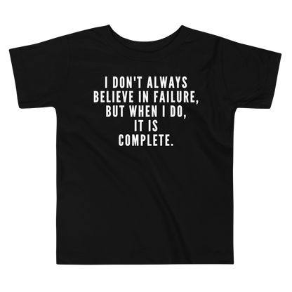 "I don't always believe in failure, but when I do, it is complete." printed on a black toddler short sleeve tee laying on a flat surface