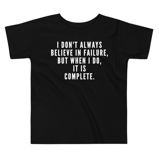 "I don't always believe in failure, but when I do, it is complete." printed on a black toddler short sleeve tee laying on a flat surface