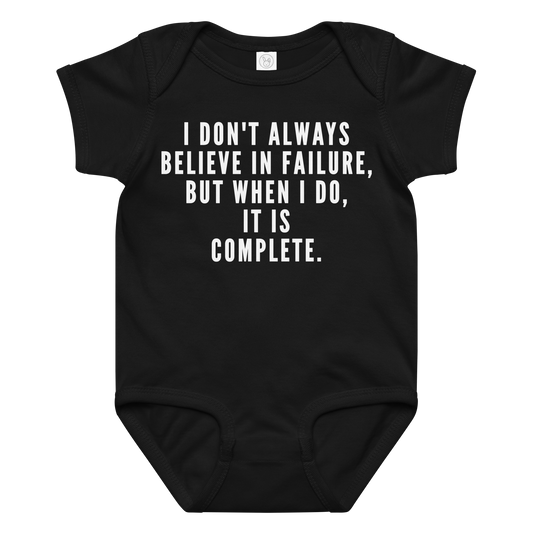 "I don't always believe in failure, but when I do, it is complete." printed on a black baby jersey bodysuit laying on a flat surface amongst other clothes