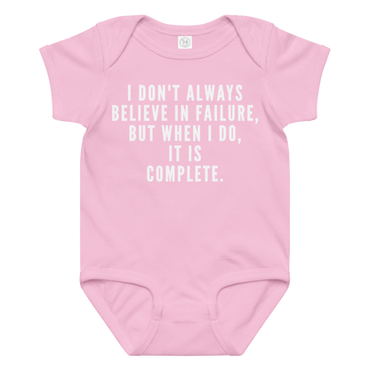 "I don't always believe in failure, but when I do, it is complete." printed on a pink baby jersey bodysuit laying on a flat surface amongst other clothes