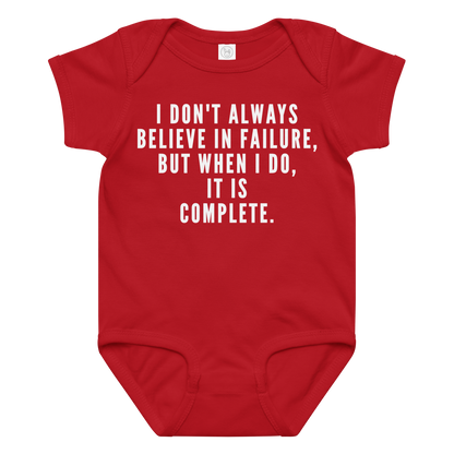 "I don't always believe in failure, but when I do, it is complete." printed on a red baby jersey bodysuit laying on a flat surface amongst other clothes