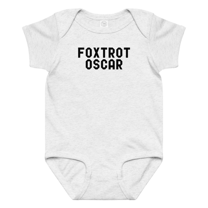 "Foxtrot Oscar" printed on a ash baby jersey bodysuit laying on a flat surface amongst other clothes