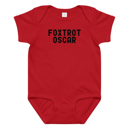 "Foxtrot Oscar" printed on a red baby jersey bodysuit laying on a flat surface amongst other clothes