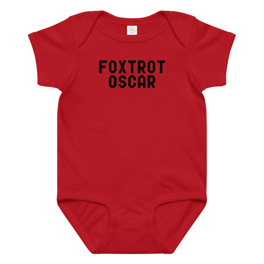 "Foxtrot Oscar" printed on a red baby jersey bodysuit laying on a flat surface amongst other clothes