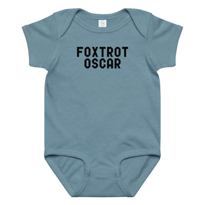 "Foxtrot Oscar" printed on a vintage indigo baby jersey bodysuit laying on a flat surface amongst other clothes