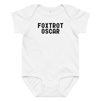 "Foxtrot Oscar" printed on a white baby jersey bodysuit laying on a flat surface amongst other clothes