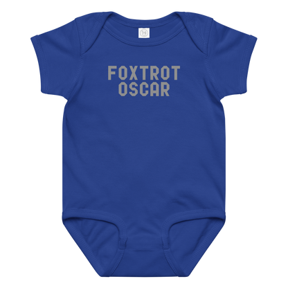 "Foxtrot Oscar" printed on a royal baby jersey bodysuit laying on a flat surface amongst other clothes
