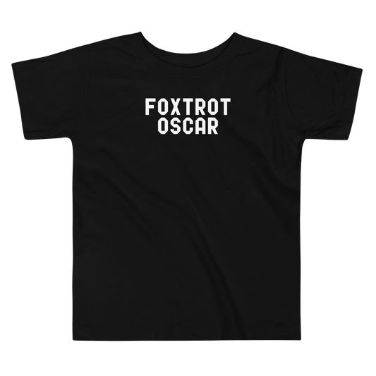 "Foxtrot Oscar" printed on a black toddler short sleeve tee laying on a flat surface