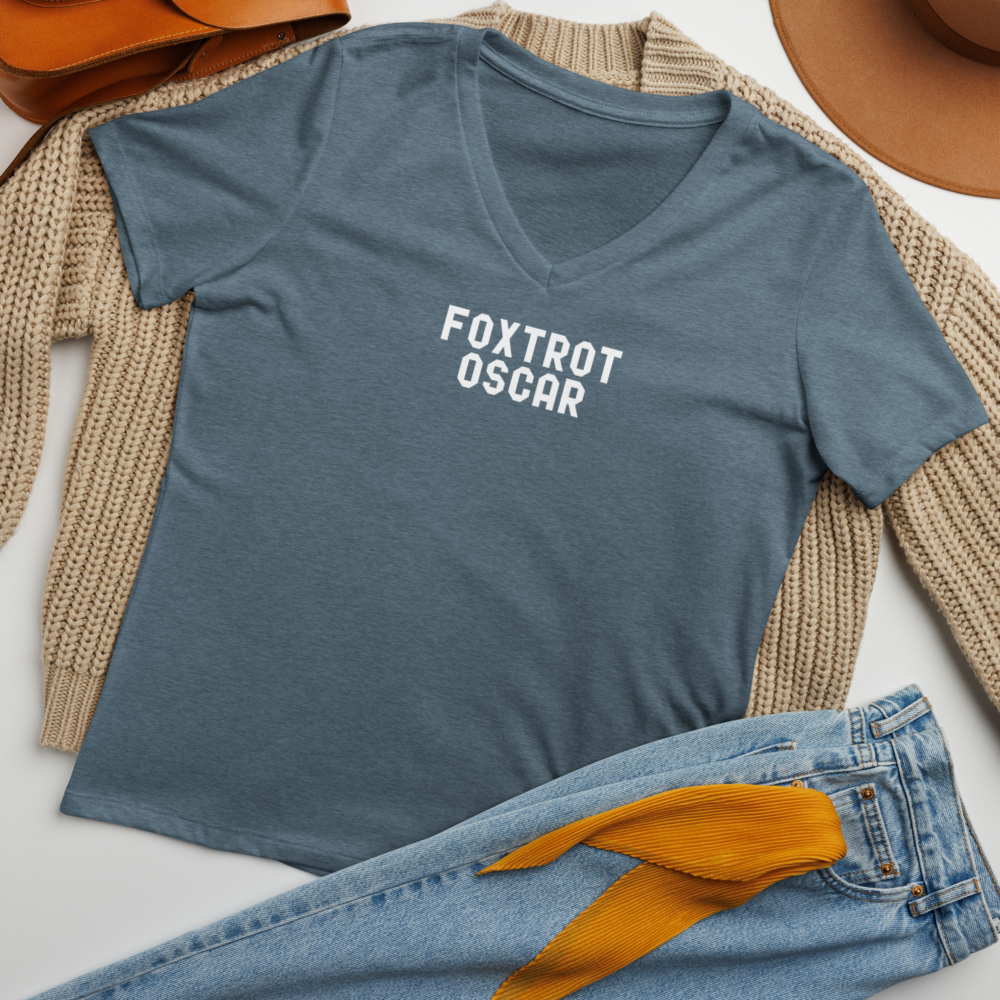 "Foxtrot Oscar" printed on a heather slate women's relaxed v-neck t-shirt laying on a flat surface amongst other clothes