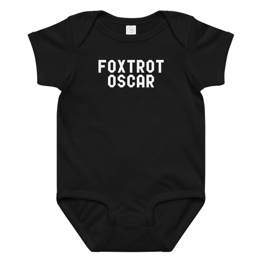 "Foxtrot Oscar" printed on a black baby jersey bodysuit laying on a flat surface amongst other clothes