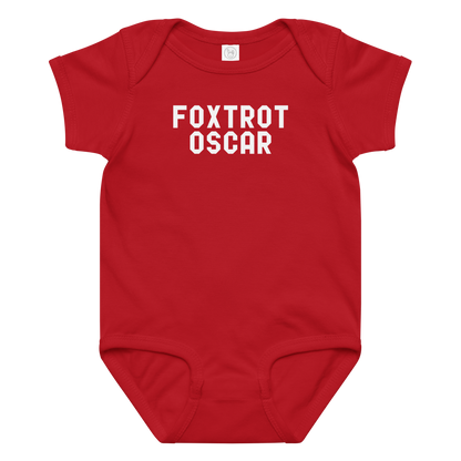 "Foxtrot Oscar" printed on a red baby jersey bodysuit laying on a flat surface amongst other clothes