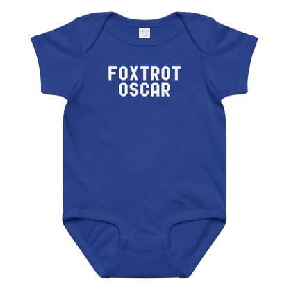"Foxtrot Oscar" printed on a royal baby jersey bodysuit laying on a flat surface amongst other clothes
