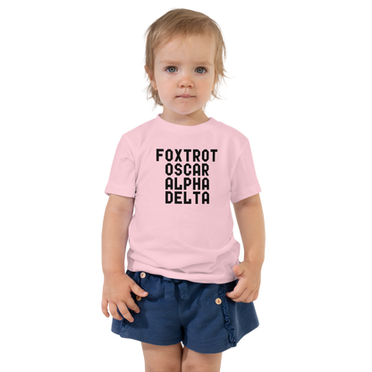 "Foxtrot Oscar Alpha Delta" printed on a pink toddler short sleeve tee worn by a female