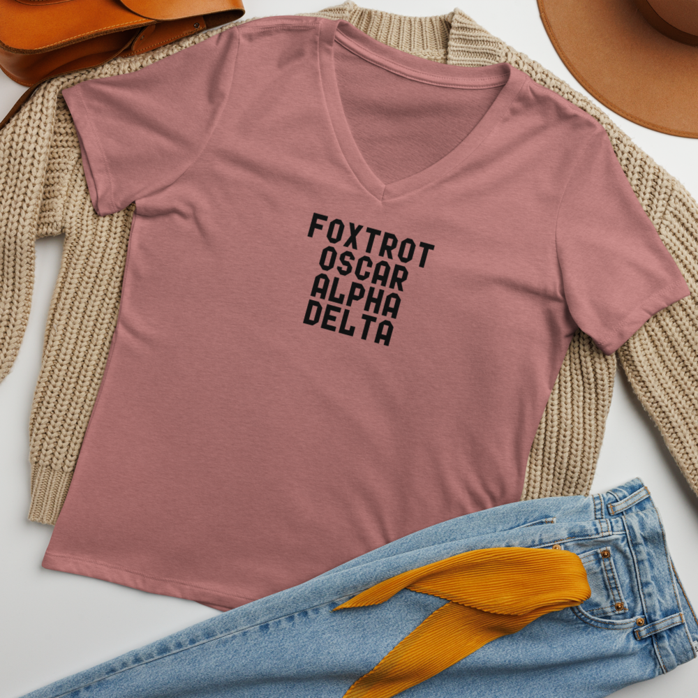 "Foxtrot Oscar Alpha Delta" printed on a heather mauve women's relaxed v-neck t-shirt laying on a flat surface amongst other clothes