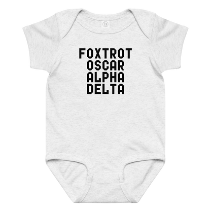 "Foxtrot Oscar Alpha Delta" printed on a ash baby jersey bodysuit laying on a flat surface amongst other clothes