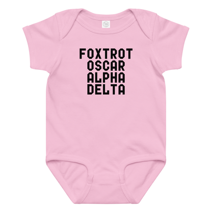 "Foxtrot Oscar Alpha Delta" printed on a pink baby jersey bodysuit laying on a flat surface amongst other clothes