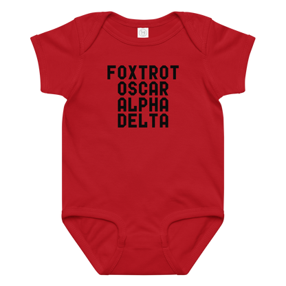 "Foxtrot Oscar Alpha Delta" printed on a red baby jersey bodysuit laying on a flat surface amongst other clothes
