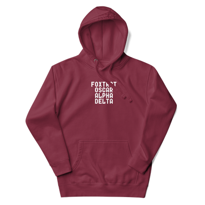 "Foxtrot Oscar Alpha Delta" printed on a maroon unisex hoodie laying on a flat surface with the hood up