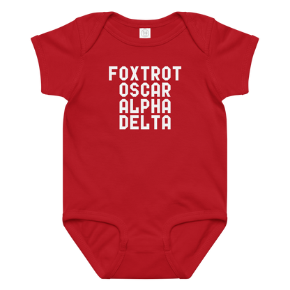 "Foxtrot Oscar Alpha Delta" printed on a red baby jersey bodysuit laying on a flat surface amongst other clothes