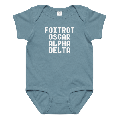 "Foxtrot Oscar Alpha Delta" printed on a vintage indigo baby jersey bodysuit laying on a flat surface amongst other clothes