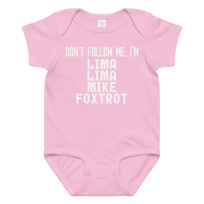 "Don’t follow me, I'm Lima Lima Mike Foxtrot" printed on a pink baby jersey bodysuit laying on a flat surface amongst other clothes